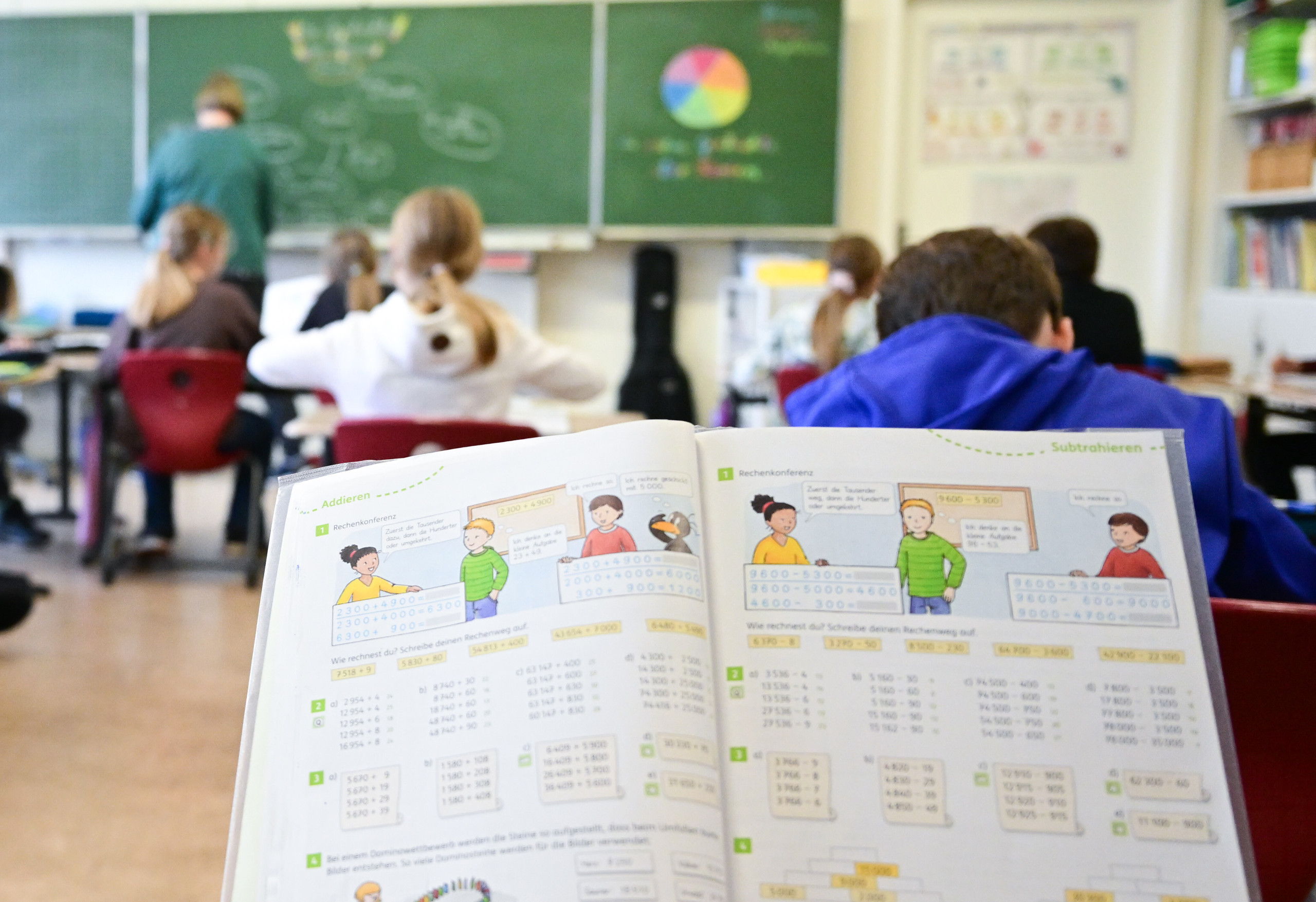 Kinder sitzen in einem Klassenraum und blicken zur Tafel.