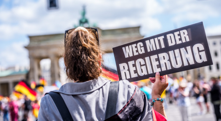 Eine Frau auf einer Demo hält ein Schild mit der Aufschrift "Weg mit der Regierung“