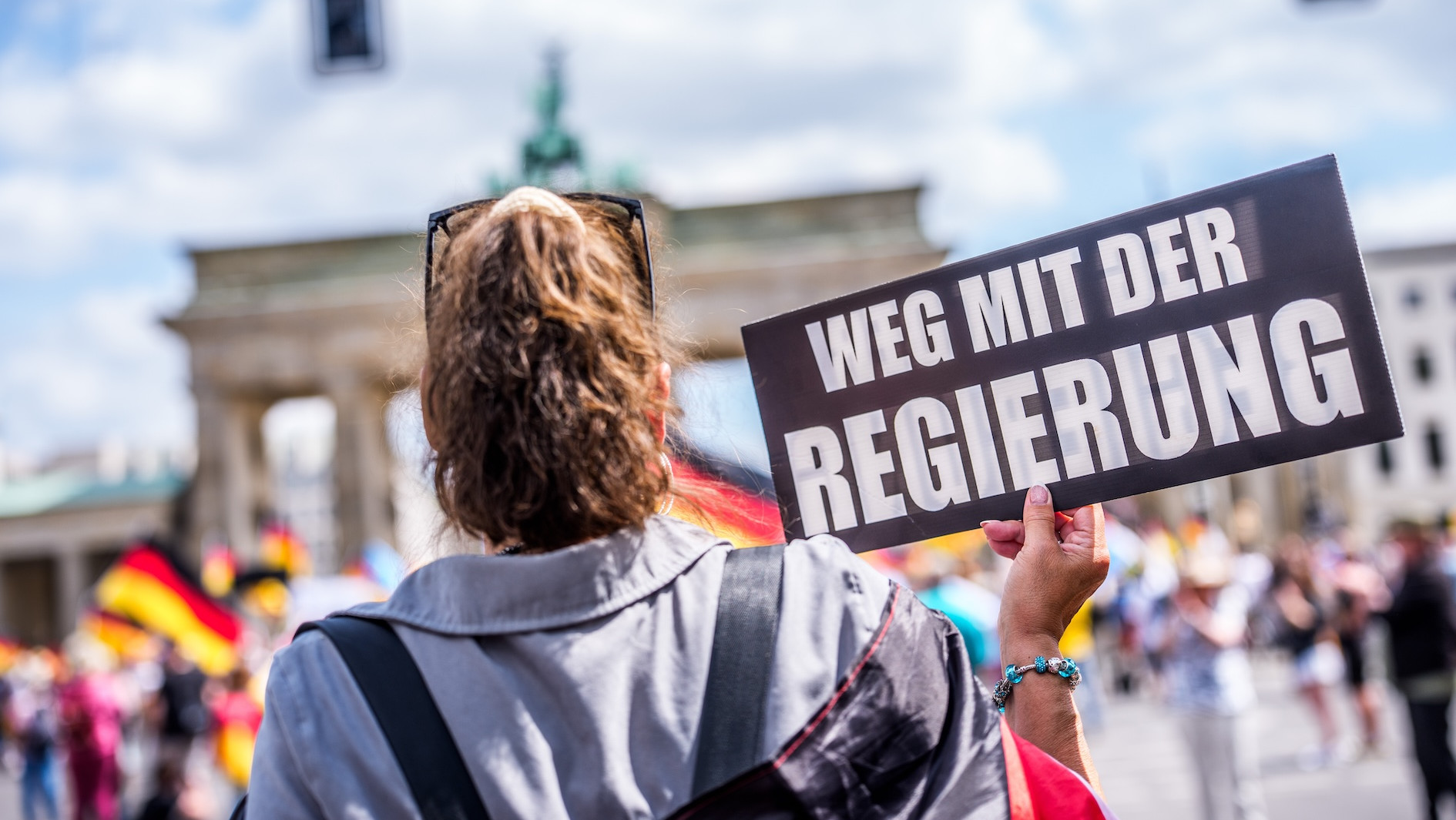 Eine Frau auf einer Demo hält ein Schild mit der Aufschrift "Weg mit der Regierung“