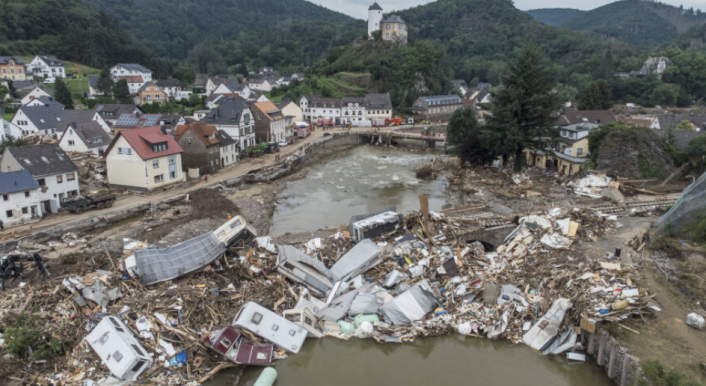 Das Bild zeigt eine Drohnenaufnahme vom 19. Juli 2021. Zu sehen sind meterhoch aufgetürmte Trümmer – Wohnwagen, Gastanks, Bäume und Schrott – an der zerstörten Brücke über die Ahr in Altenahr-Kreuzberg wenige Tage nach der Flutkatastrophe. (Bild: picture alliance/dpa | Boris Roessler)