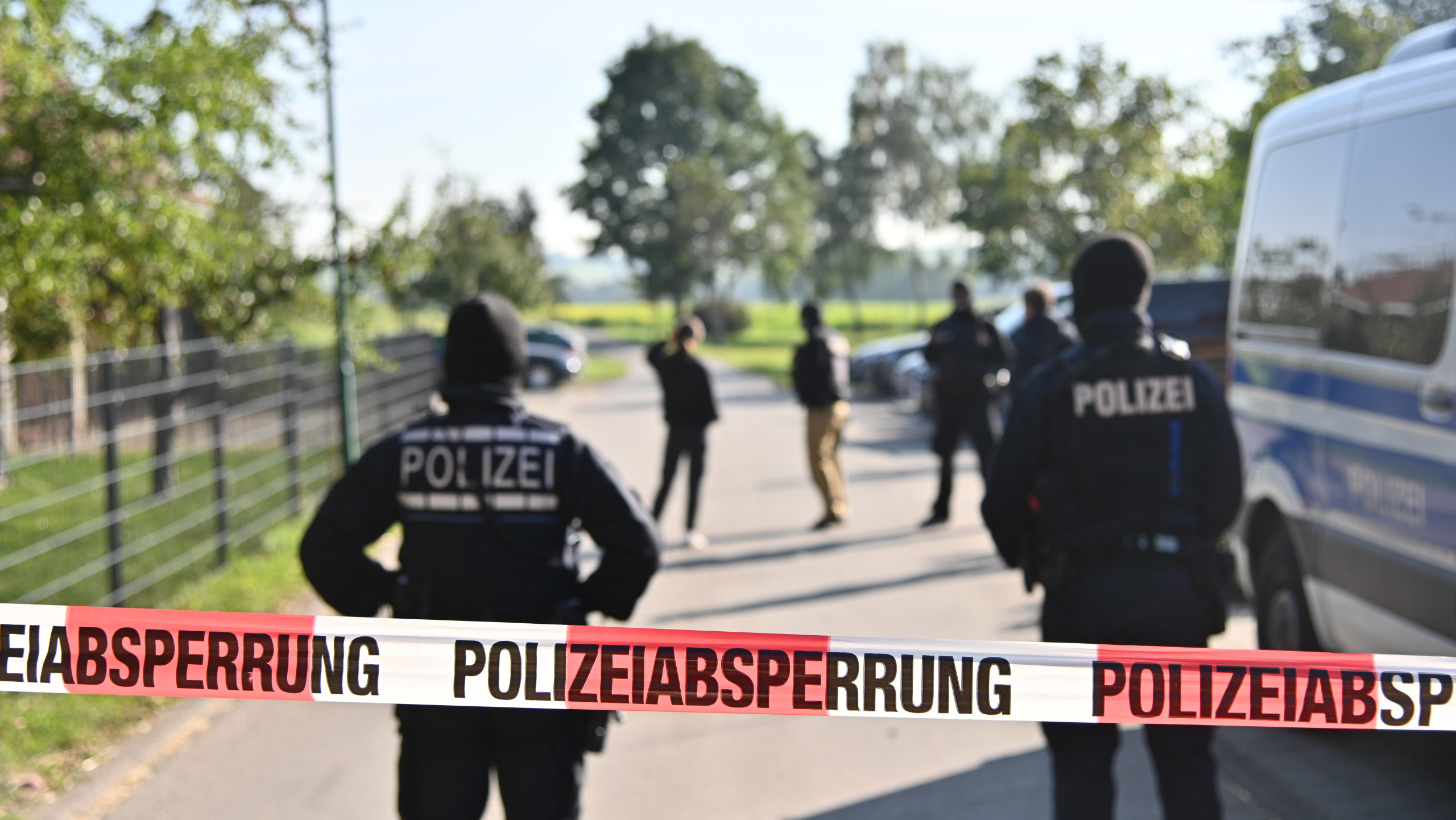 Einsatzkräfte der Polizei stehen hinter einer Polizeiabsperrung. Bundesinnenministerin Faeser (SPD) hat eine weitere rechtsextremistische Vereinigung verboten. Einsatzkräfte der Polizei durchsuchten am Mittwochmorgen 26 Wohnungen von 39 Mitgliedern sowie Räume des Vereins «Die Artgemeinschaft - Germanische Glaubens-Gemeinschaft wesensgemäßer Lebensgestaltung» in zwölf Bundesländern, wie das Innenministerium in Berlin mitteilte. (zu dpa "Razzien gegen völkische Siedler - Faeser verbietet «Artgemeinschaft»")