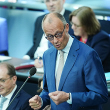 Bundeskanzler Merz steht hinter einem Mikrofon.