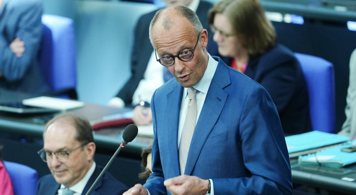 Bundeskanzler Merz steht hinter einem Mikrofon.