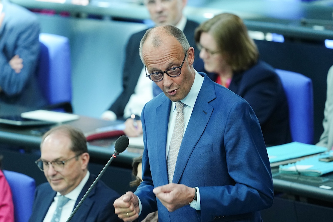 Bundeskanzler Merz steht hinter einem Mikrofon.