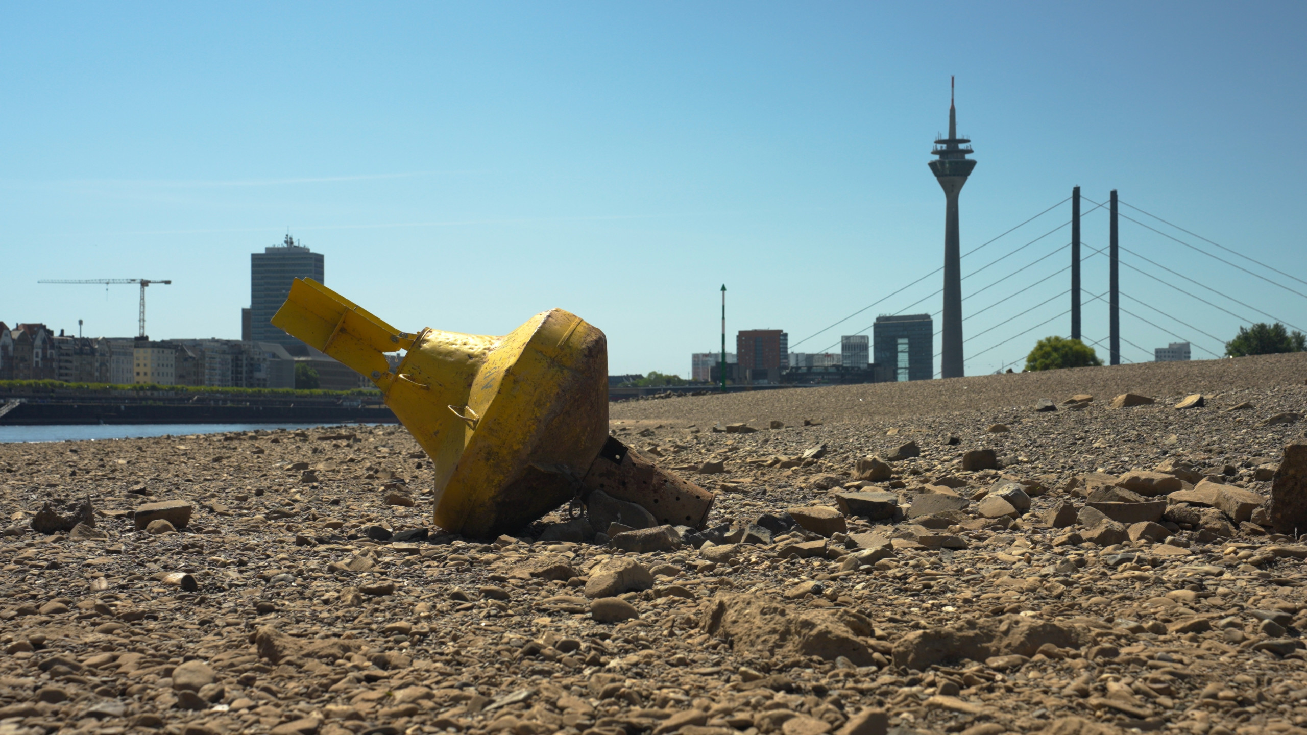 Eine gelbe Boje liegt trocken auf braunem Sand. Eigentlich sollte sie schwimmen.