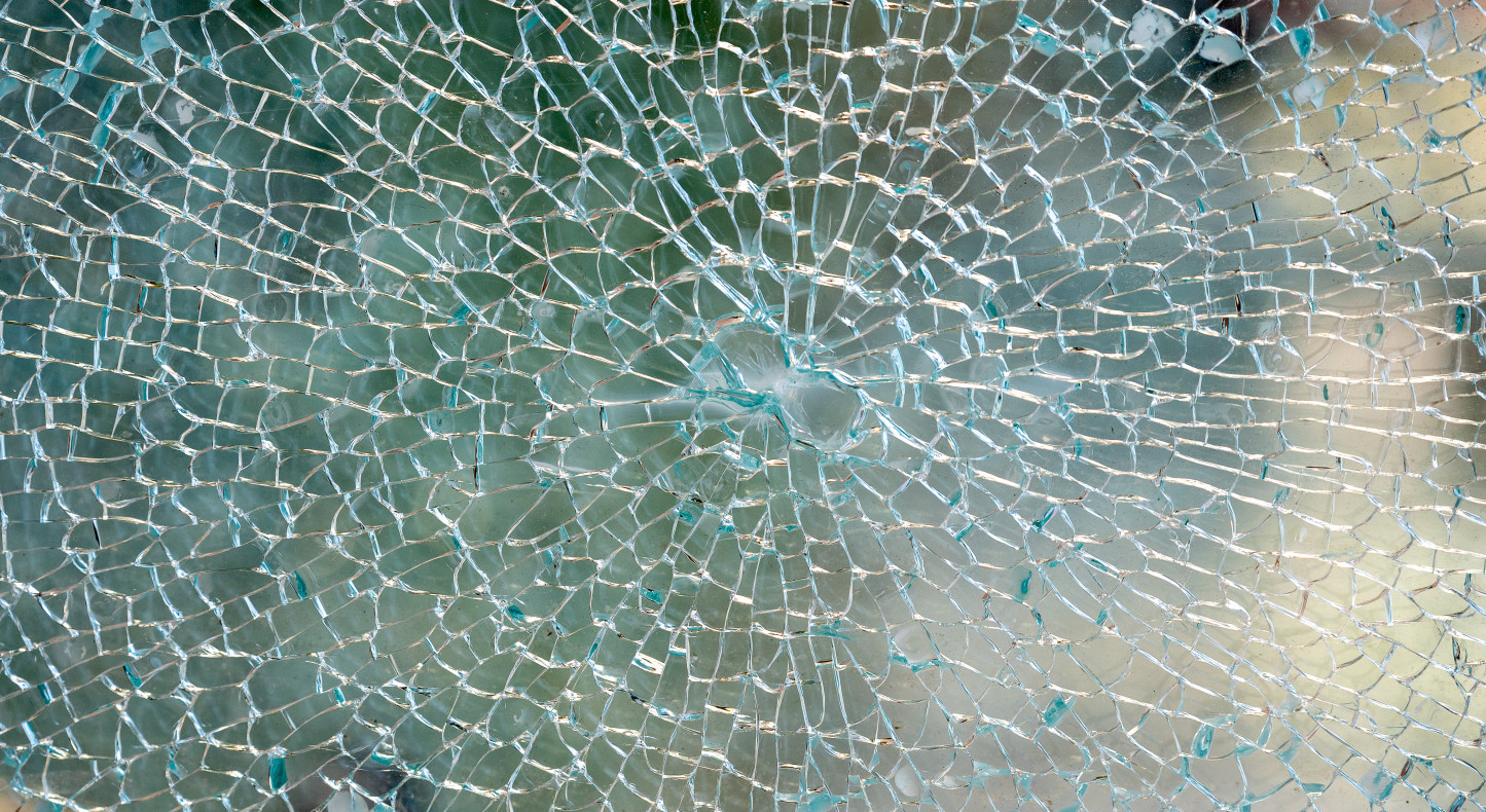 Vandalsimus: Detail eines zerborstenen Glases am Wetterschutzglas eines oeffentlichen Telefon-Fernsprechers. Das