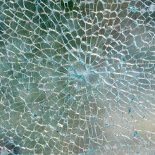 Vandalsimus: Detail eines zerborstenen Glases am Wetterschutzglas eines oeffentlichen Telefon-Fernsprechers. Das zersplitterte Glas mit einem Loch, von dem der Schaden ausging als Nahaufnahme.