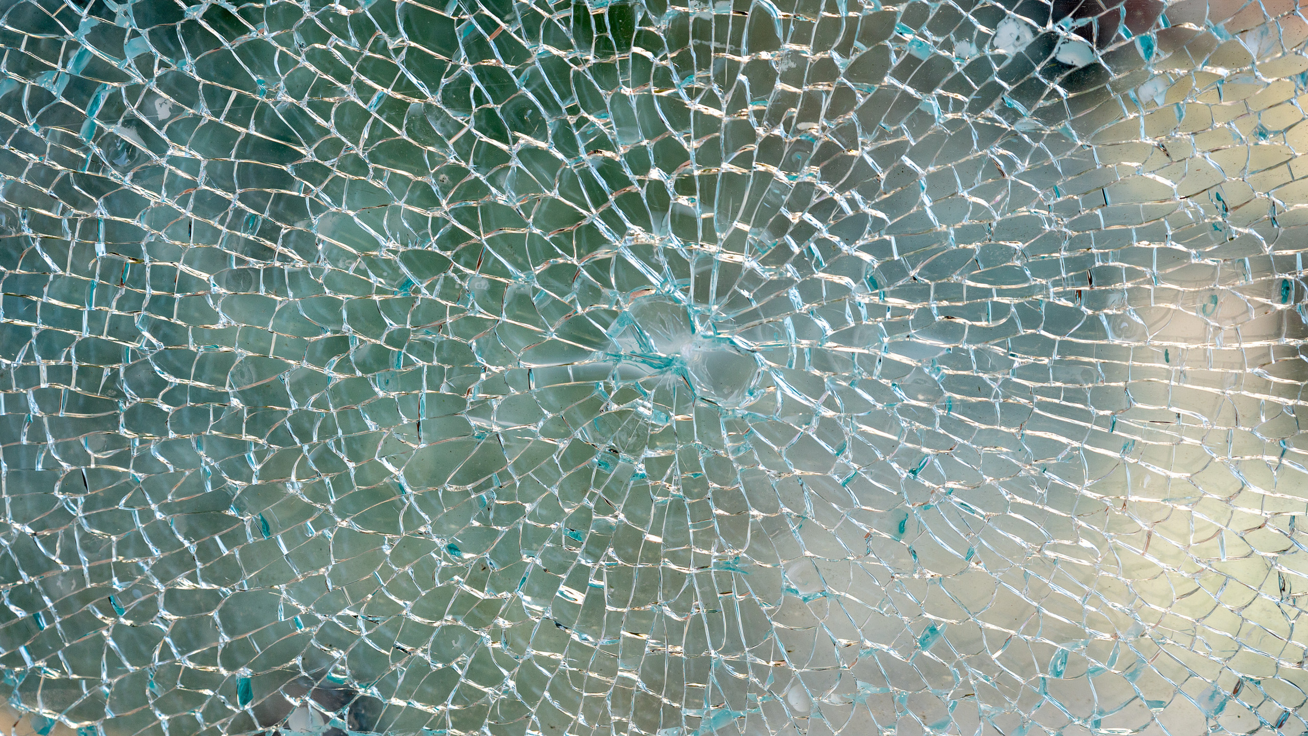 Vandalsimus: Detail eines zerborstenen Glases am Wetterschutzglas eines oeffentlichen Telefon-Fernsprechers. Das zersplitterte Glas mit einem Loch, von dem der Schaden ausging als Nahaufnahme.