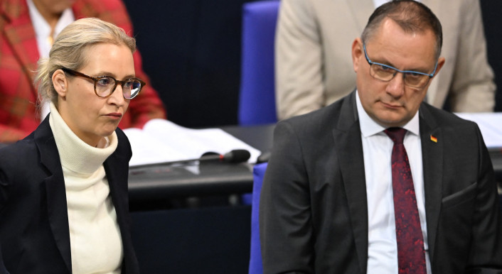 Die AfD-Spitze Alice Weidel und Tino Chrupalla sitzen im Plenum des Bundestags. Hinter ihnen weitere Bundestagsabgeordnete der AfD, Weidel und Chrupalla schauen genervt.