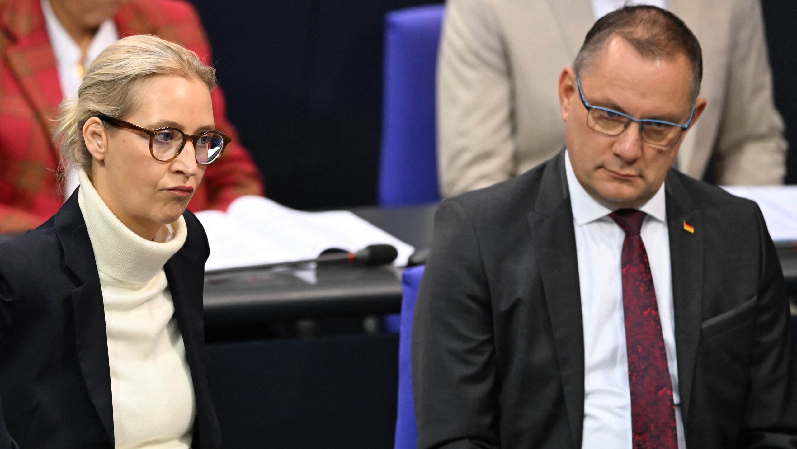 Die AfD-Spitze Alice Weidel und Tino Chrupalla sitzen im Plenum des Bundestags. Hinter ihnen weitere Bundestagsabgeordnete der AfD, Weidel und Chrupalla schauen genervt.