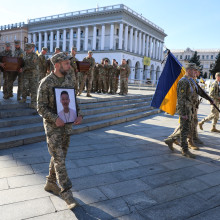 Bei einer Trauerfeier in Kiew trägt ein ukrainischer Soldat das Porträt eines Gefallenen.