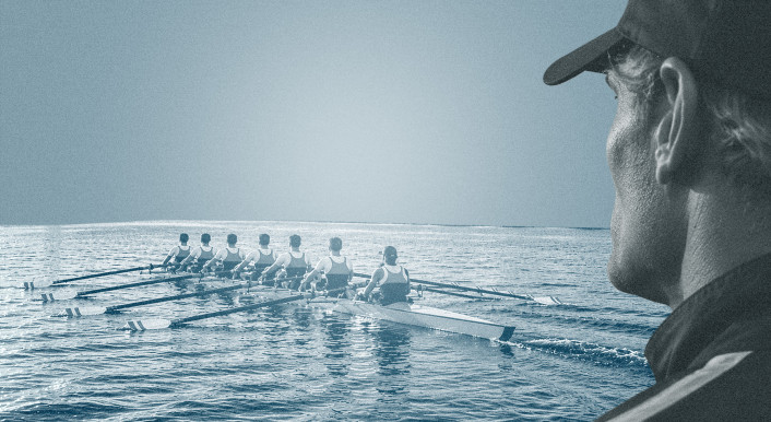 Ein Rudertrainer beobachtet ein Ruderteam im Achterboot beim Training auf offenem Wasser.