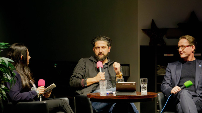 Marcus Kottmann und Aladin El-Mafaalani sitzen auf der Bühne in der Lebendigen Bibliothek in Bottrop und diskutieren mit Jugendreporterin Aylin Çerik