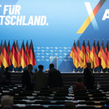 Deutschlandfahnen, leere Sitzreihen, AfD-Slogan "Zeit für Deutschland" sind zu sehen.